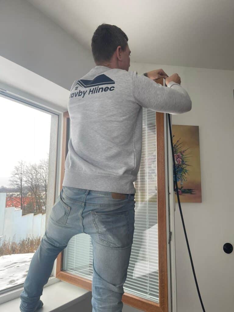 Technik při seřizování plastového okna a kontrole těsnění v rámci servisu oken pro zlepšení těsnosti a snížení tepelných ztrát.